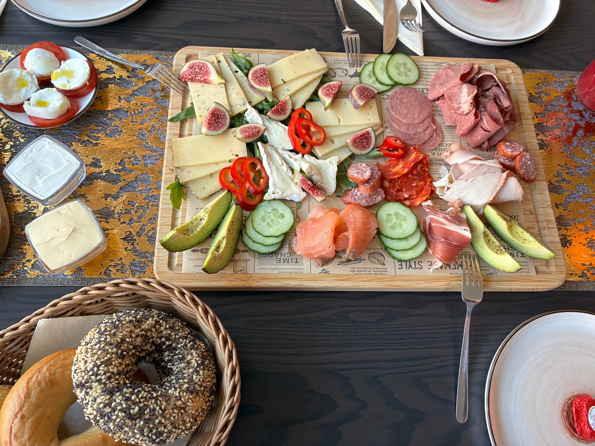 Frühstücksplatte mit handverlesener Wurst, Käse, Lachs, Avocado und frischem Bagel
